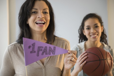 Mother holding fan flag for athlete daughter