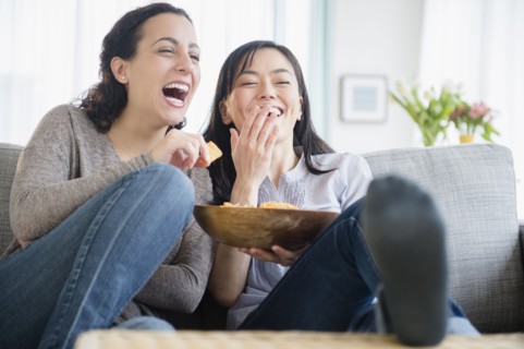 Women laughing on sofa together