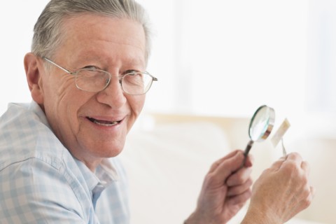 Senior Caucasian man examining stamp with magnifying glass