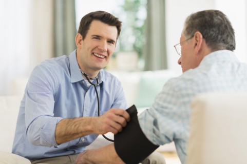 Caucasian doctor taking patient's blood pressure at home