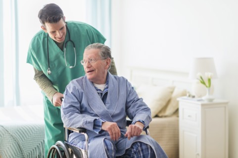Caucasian nurse wheeling patient in home