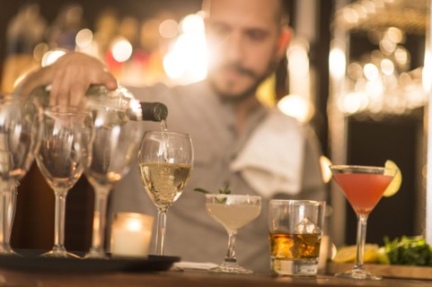 Hispanic bartender pouring drinks at bar