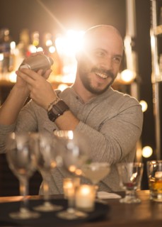 Hispanic bartender making drinks at bar