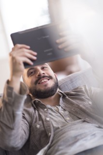 Hispanic man using digital tablet on sofa