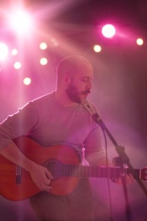 Hispanic musician playing guitar on stage