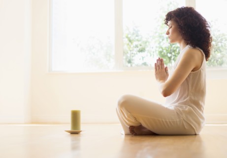 Hispanic woman meditating with candle