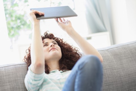 Hispanic woman using digital tablet on sofa