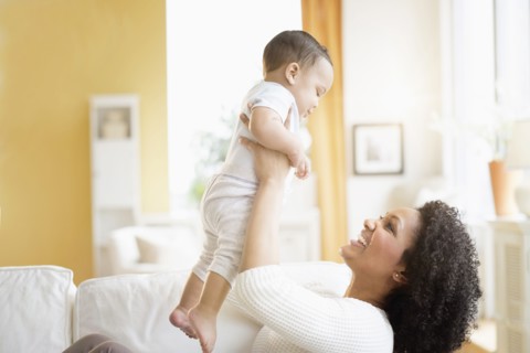 Mixed race mother playing with baby on sofa