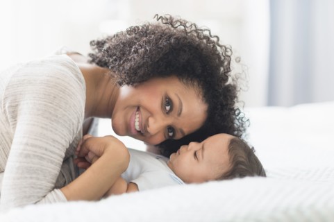 Mixed race mother playing with baby on bed