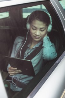 Mixed race teenage girl using digital tablet in backseat of car