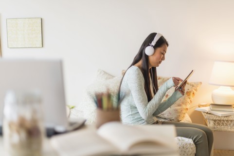 Mixed race teenage girl using digital tablet on bed