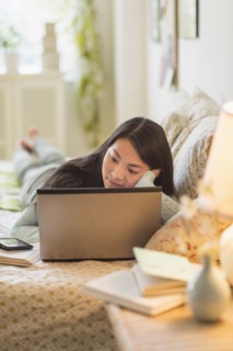 Mixed race teenage girl doing homework on bed
