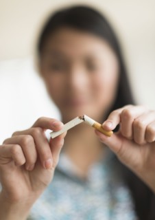 Mixed race teenage girl breaking cigarette in half