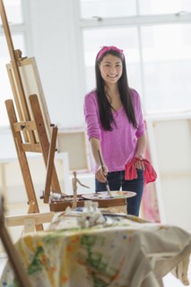 Mixed race teenage girl painting in studio