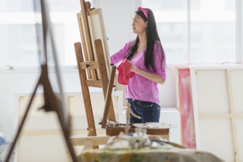Mixed race teenage girl painting in studio