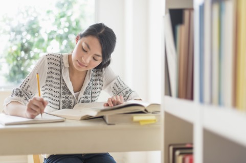 Mixed race teenage girl studying in library