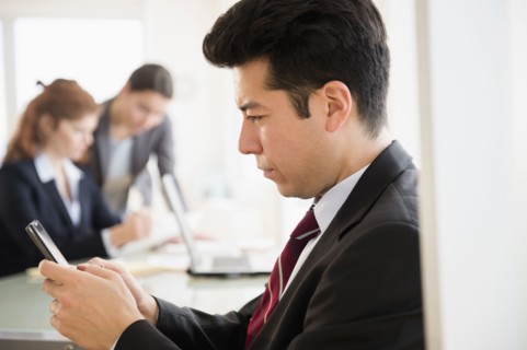 Businessman using cell phone in office