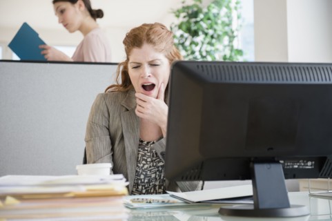 Caucasian businesswoman yawning at desk