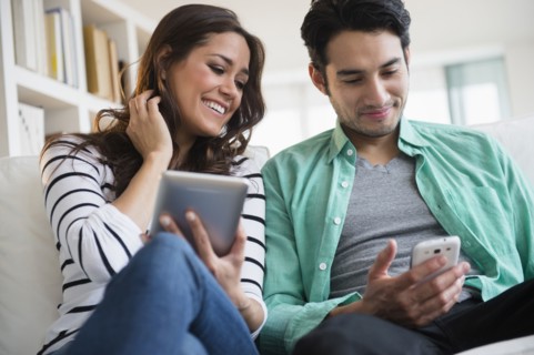 Couple using technology together on sofa