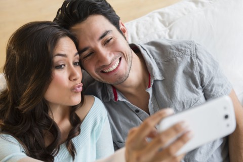Couple taking pictures together on sofa