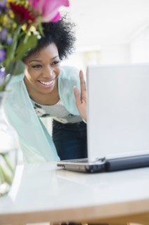 African American woman video chatting with laptop