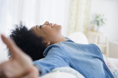 African American woman with arms outstretched on sofa