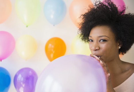 African American woman blowing up balloon for party