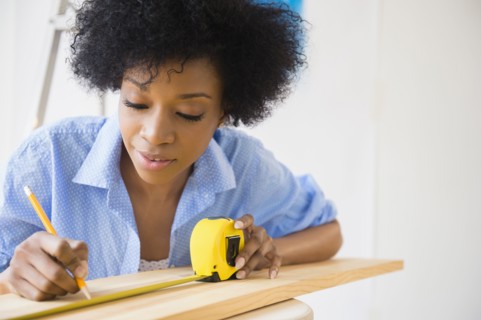 African American woman measuring wood
