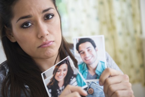 Woman holding torn picture of herself with ex-boyfriend