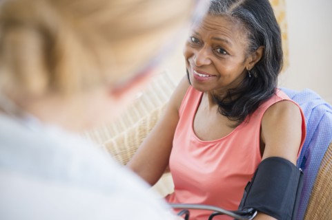Woman having blood pressure taken on sofa