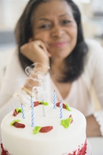 Mixed race woman blowing out birthday candles on cake
