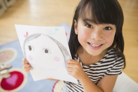 Filipino girl displaying drawing in bedroom