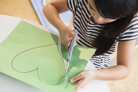 Filipino girl cutting heart shape out of paper