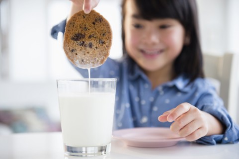 Filipino girl dunking cookie in milk