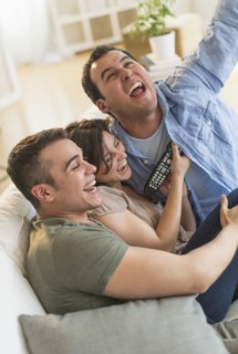 Hispanic friends cheering at television in living room