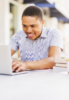 African American man using laptop at sidewalk cafe