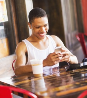 African American man using cell phone at cafe