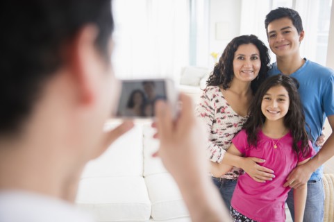 Hispanic family taking cell phone photograph in living room