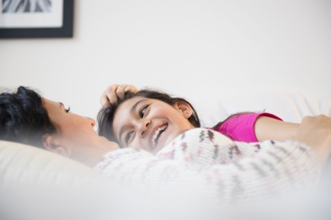 Hispanic mother and daughter relaxing together on bed