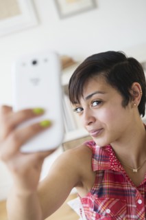 Mixed race woman taking selfie with cell phone