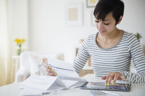 Mixed race woman paying bills on digital tablet