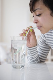 Mixed race woman drinking water with straw