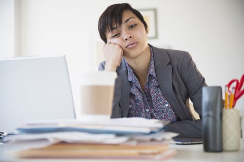 Bored mixed race businesswoman sitting at office desk