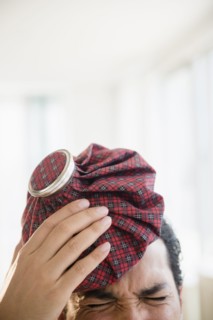 Mixed race man holding ice pack to head