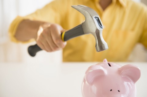 Close up of mixed race man holding hammer over piggy bank