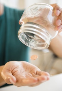 Close up of mixed race man pouring penny out of jar