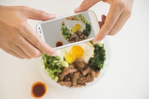 Close up of mixed race man photographing food with cell phone