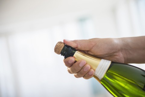 Close up of mixed race man opening bottle of champagne