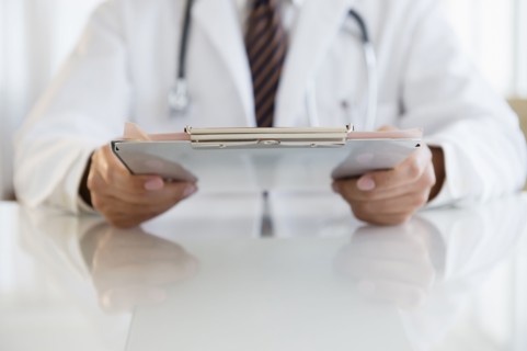 Close up of mixed race doctor holding clipboard