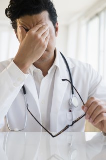 Close up of upset mixed race doctor rubbing his forehead